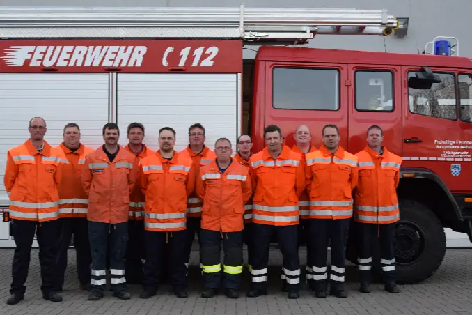 Die 1. Gruppe in orangefarbener Schutzkleidung vor einem Löschfahrzeug